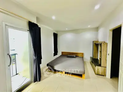 Spacious bedroom with minimalist design and balcony access, featuring modern furniture and ample natural light.