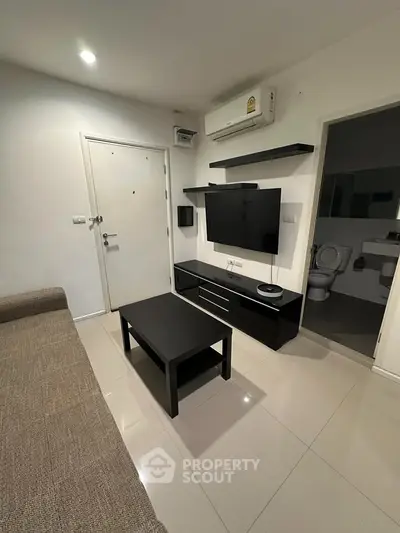 Modern living room with sleek furniture and wall-mounted TV in a cozy apartment.