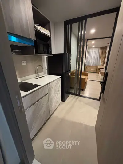 Modern compact kitchen with sleek design and open layout leading to cozy living area.
