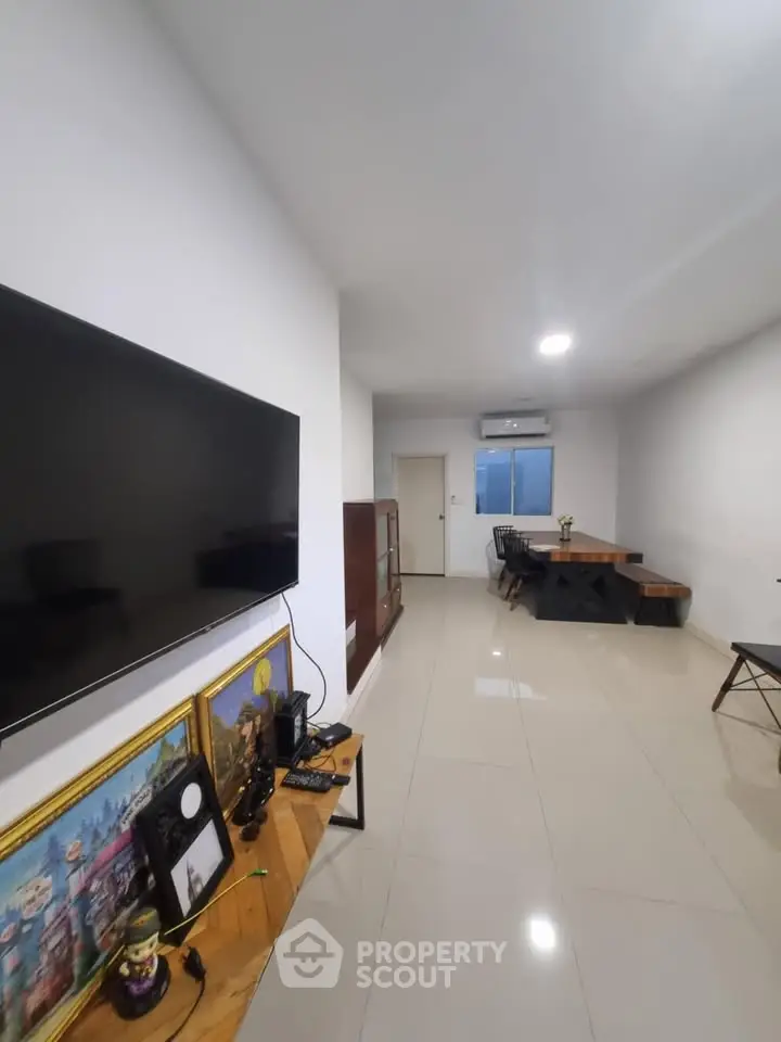 Spacious living room with modern decor and wall-mounted TV, perfect for relaxation and entertainment.