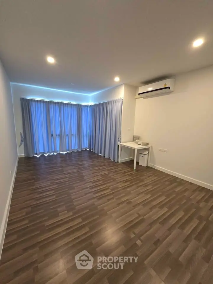Spacious modern living room with wooden flooring and large windows.