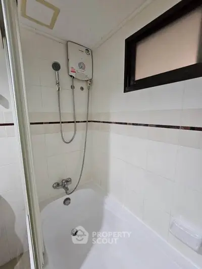 Compact bathroom with bathtub and water heater, ideal for small apartments.