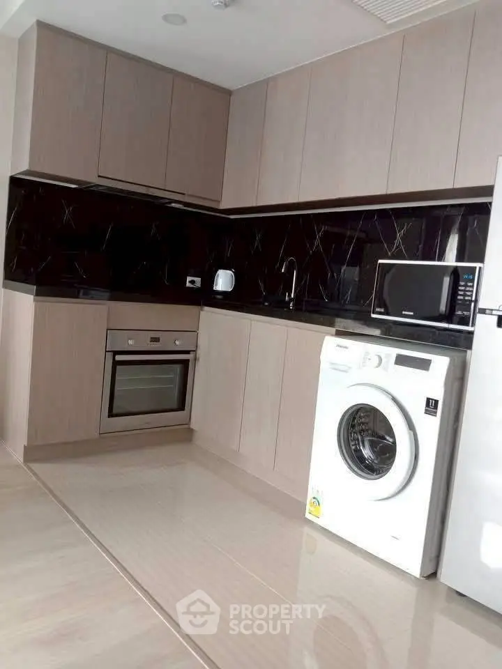 Modern kitchen with sleek cabinetry, built-in oven, and washing machine.
