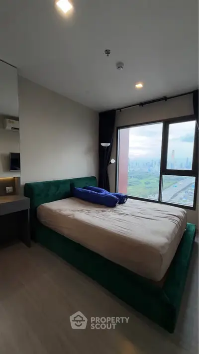 Modern bedroom with large window offering stunning city view, featuring a cozy bed and sleek design.