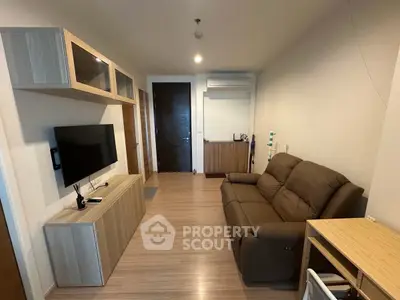 Modern living room with sleek furniture and wall-mounted TV in cozy apartment.