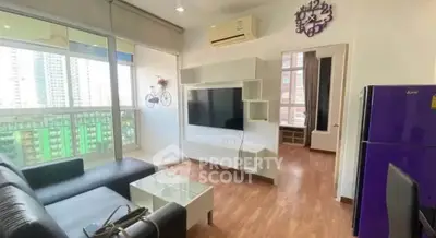 Modern living room with balcony view, sleek furniture, and wall-mounted TV in a stylish apartment.
