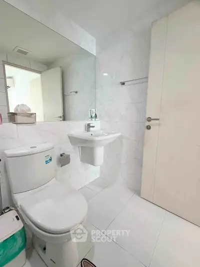 Modern bathroom with sleek white fixtures and large mirror in a contemporary apartment.