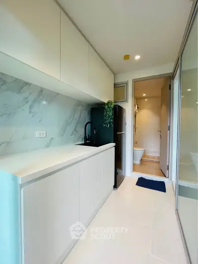 Modern kitchen with sleek cabinetry and marble backsplash in a bright apartment