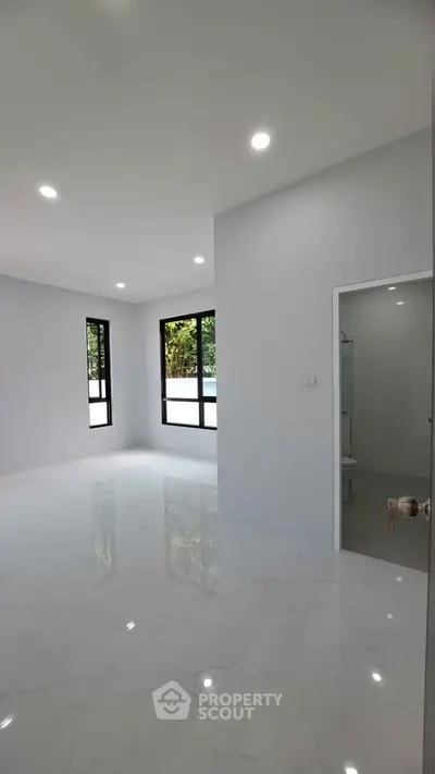 Spacious modern living room with large windows and glossy white flooring