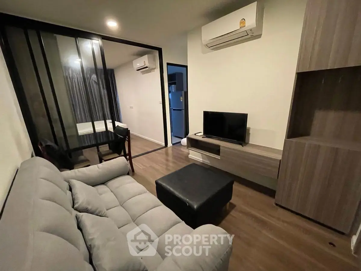 Modern living room with sleek design, featuring a comfortable sofa, TV, and air conditioning.