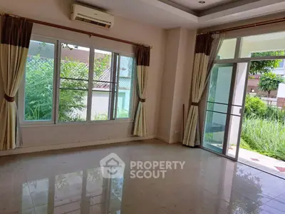 Spacious living room with large windows and garden view, perfect for natural light lovers.