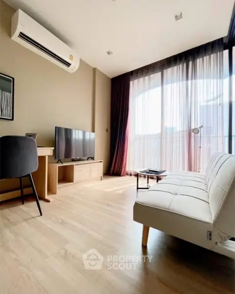Modern living room with natural light, sleek furniture, and wooden flooring.