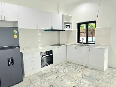 Modern kitchen with sleek white cabinets and marble flooring