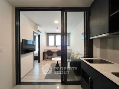 Modern open-plan living room with sleek kitchen and cozy seating area in a stylish apartment.
