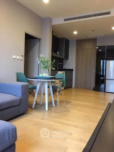 Modern living room with open kitchen, stylish furniture, and wooden flooring in a cozy apartment.