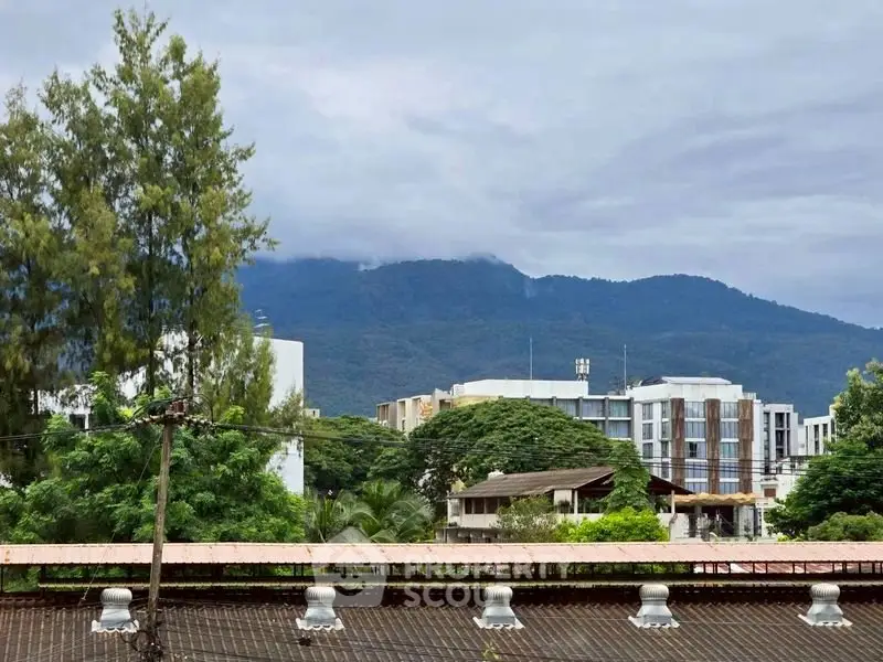 Scenic view of modern buildings with lush greenery and mountain backdrop, ideal for serene living.