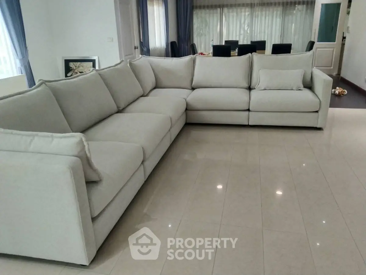 Spacious living room with elegant L-shaped sofa and polished tile flooring, perfect for modern family gatherings.