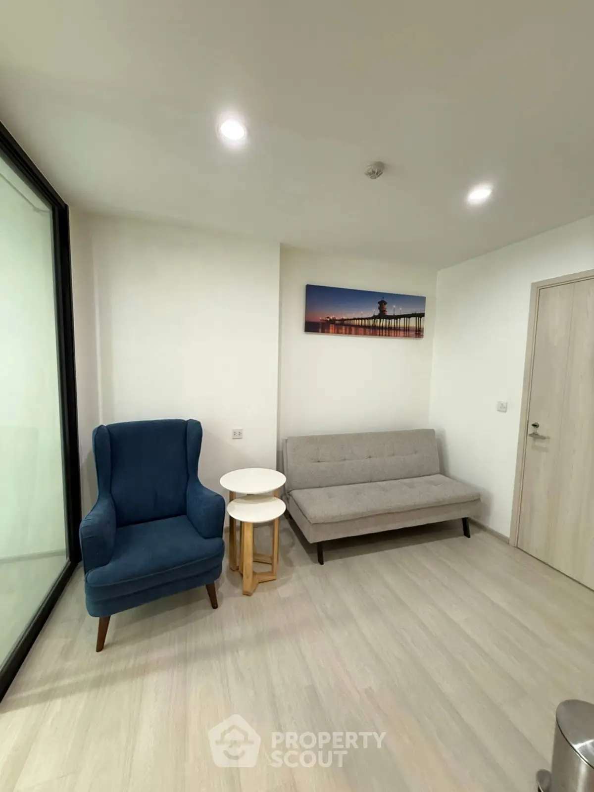 Modern living room with stylish armchair and sofa, featuring minimalist decor and bright lighting.