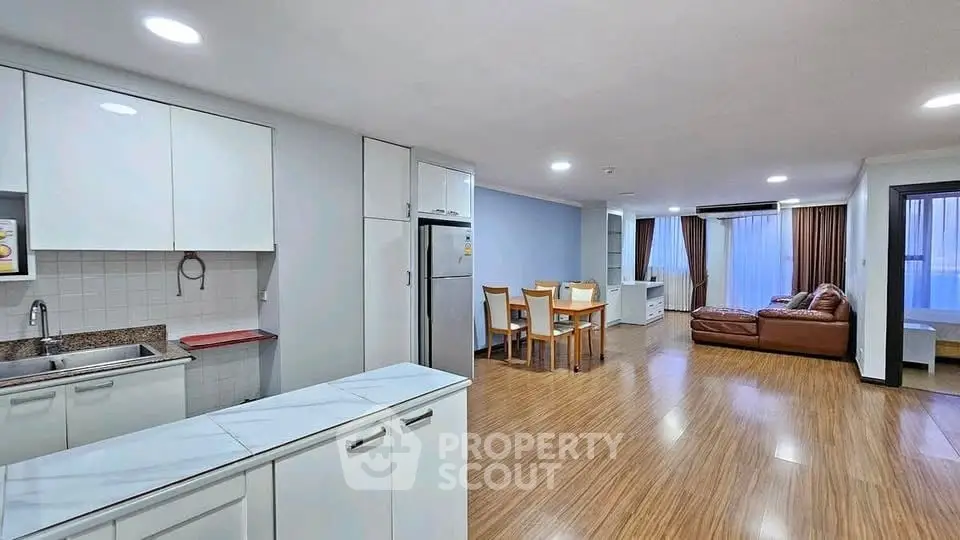 Spacious open-plan living room and kitchen with modern furnishings and wooden flooring.