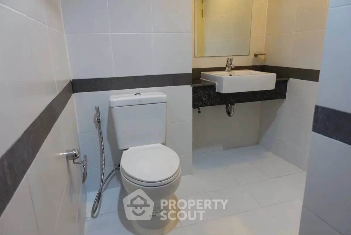 Modern bathroom with sleek white tiles and contemporary fixtures.