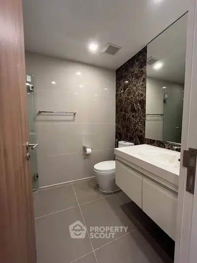 Modern bathroom with sleek design, featuring a large mirror and elegant fixtures.