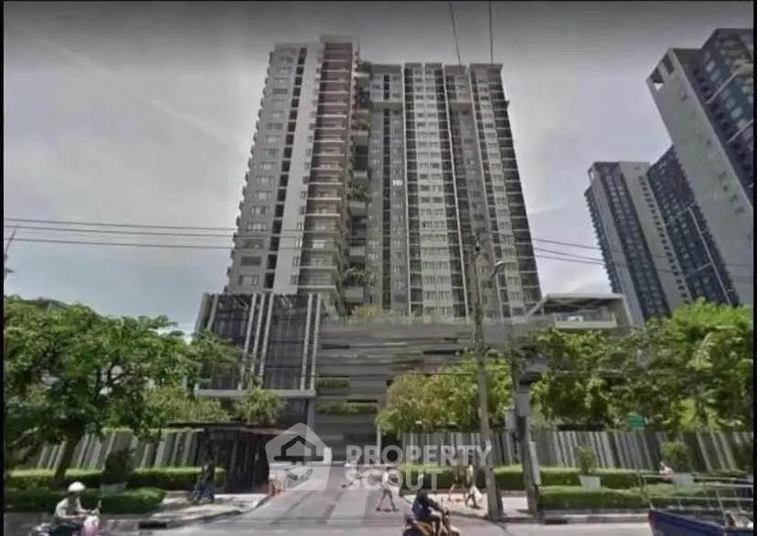 Modern high-rise building with lush greenery and urban surroundings.