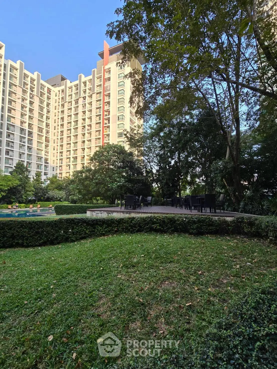 Luxurious residential building with lush garden and outdoor seating area, perfect for relaxation.
