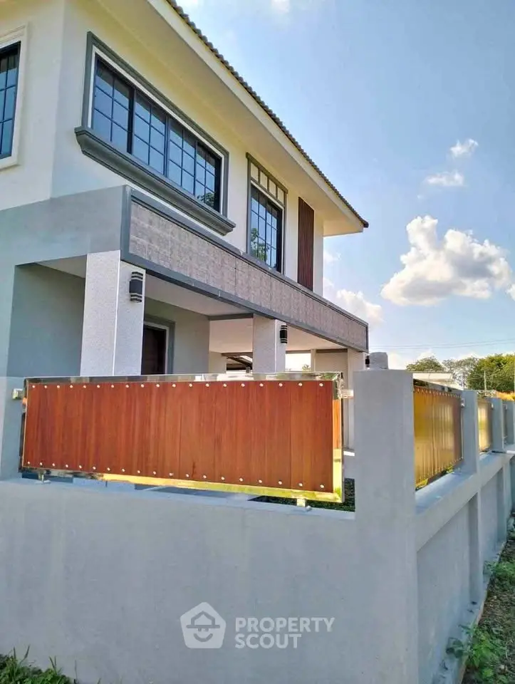 Modern two-story house with stylish facade and wooden fence under clear blue sky.