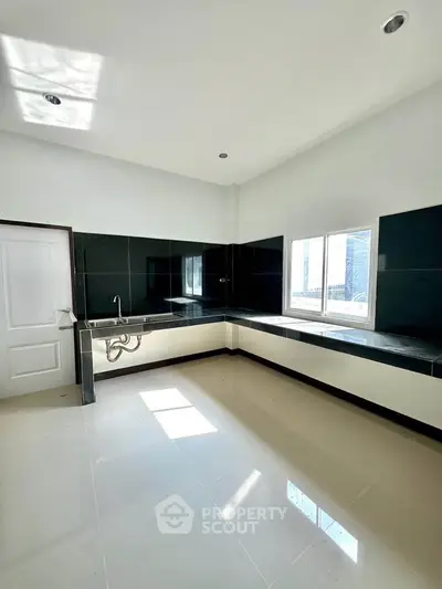 Spacious modern kitchen with sleek black countertops and ample natural light.
