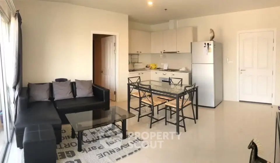 Modern open-layout living room and kitchen with sleek furniture and natural light.