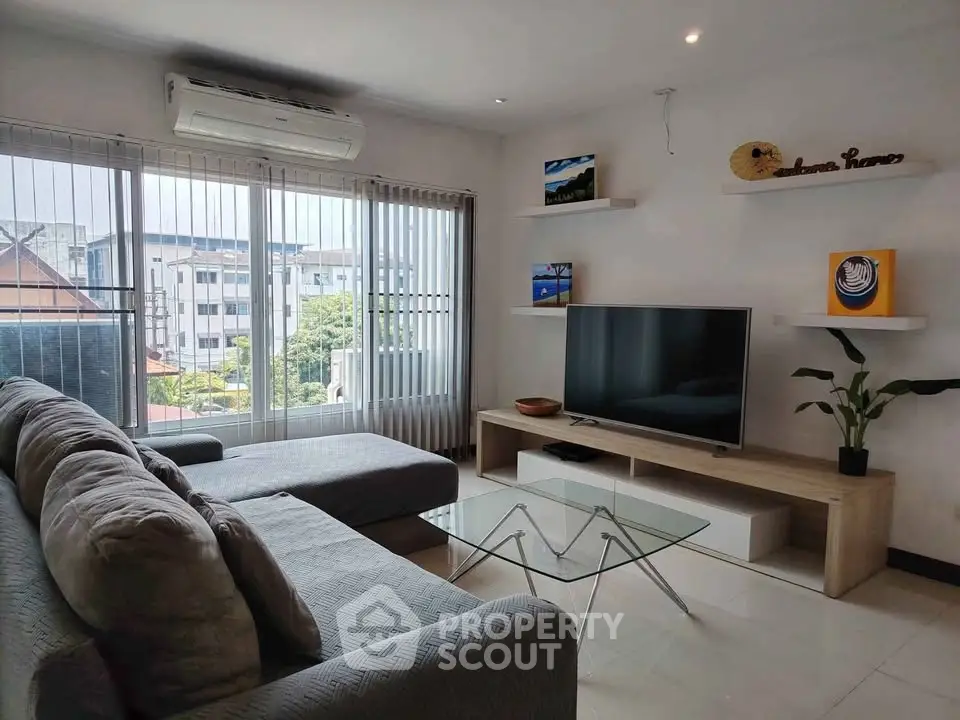 Modern living room with large windows, stylish sofa, and sleek entertainment center.