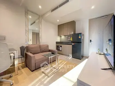 Modern living room with sleek furniture and compact kitchen in a stylish apartment.