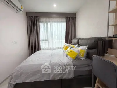 Cozy modern bedroom with plush bed and natural light through large window.