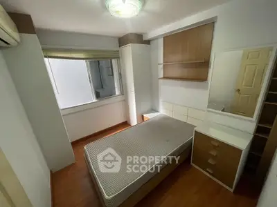 Cozy bedroom with wooden flooring and built-in storage, perfect for modern living.