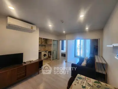 Modern living room with open layout and washing machine, featuring sleek furniture and bright lighting.
