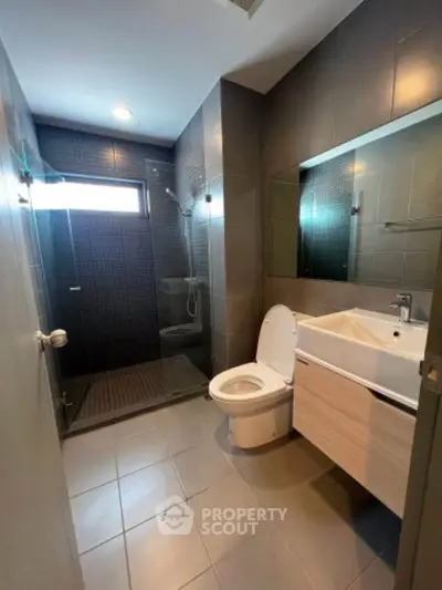 Modern bathroom with sleek design, featuring a glass shower enclosure and contemporary fixtures.