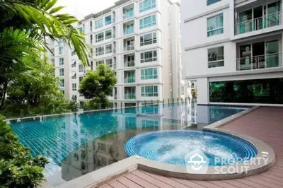 Luxurious condominium with stunning pool and jacuzzi area, surrounded by lush greenery.