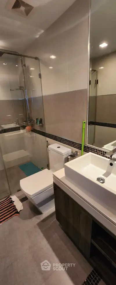 Modern bathroom with glass shower and sleek vanity in contemporary apartment.