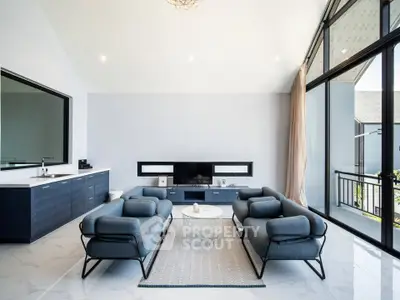 Spacious modern living room with sleek furniture and large windows offering natural light.