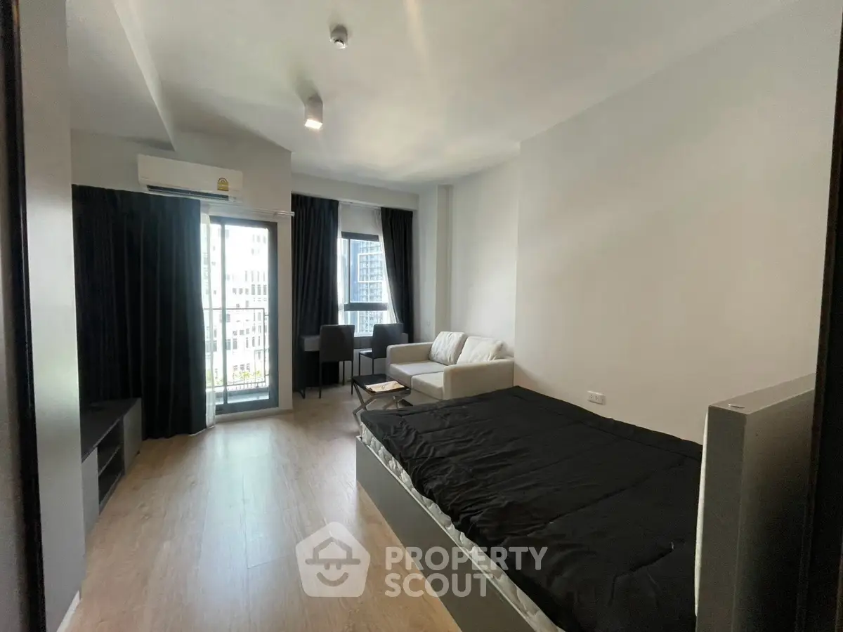 Modern studio apartment with cozy living area and city view balcony.