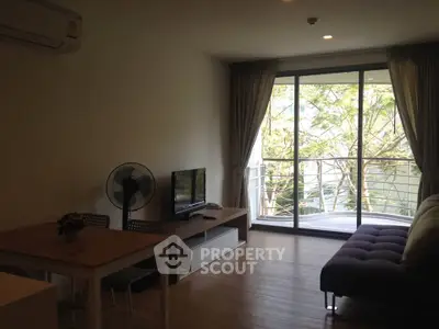 Spacious living room with balcony view, modern furniture, and natural light.