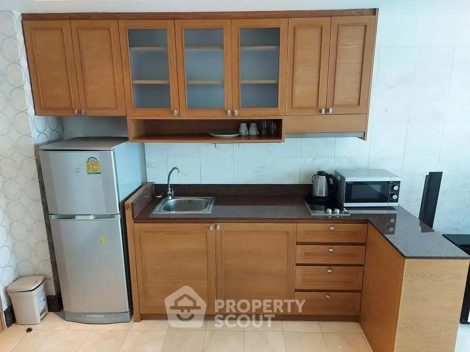Modern kitchen with wooden cabinets, stainless steel fridge, and appliances.