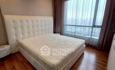 Spacious bedroom with large window offering city views and elegant furnishings.