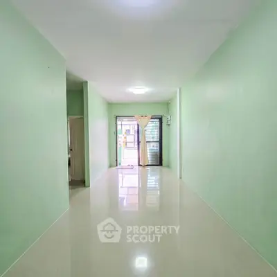 Spacious empty room with glossy floors and mint green walls, perfect for customization.