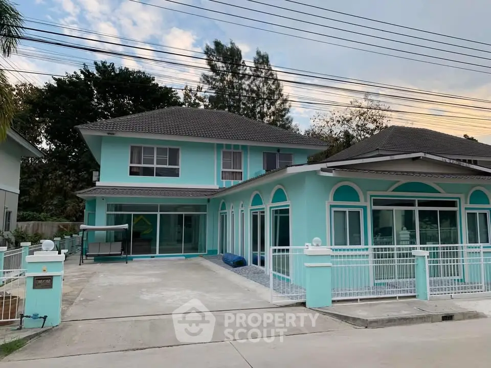 Charming turquoise two-story house with spacious driveway and modern design.