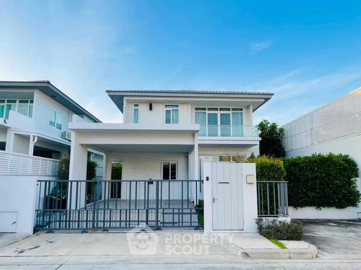 Modern two-story house with gated entrance and driveway in a serene neighborhood.