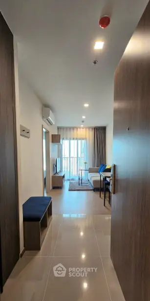 Modern apartment entrance leading to a cozy living room with natural light and stylish decor.