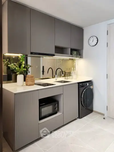 Modern kitchen with sleek cabinetry, built-in microwave, and washing machine, perfect for urban living.