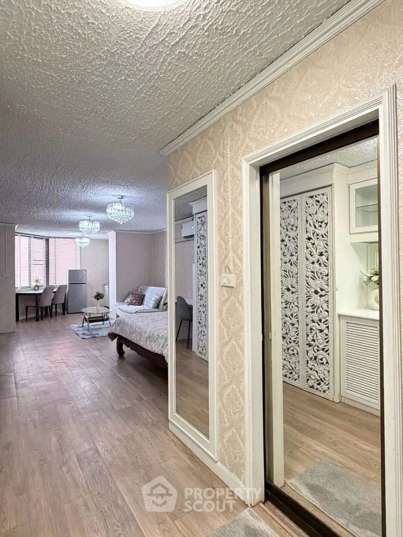 Spacious bedroom with elegant decor and large mirrors, featuring a cozy seating area and stylish lighting.