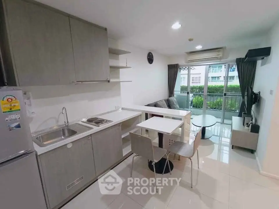 Modern open-layout kitchen and living room with balcony view in a stylish apartment.